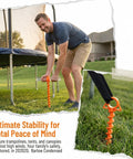 Man installing Beefy Ground Anchors For Heavy Duty Screw In Tent Stakes Built For High Wind And Loose Sand, securing trampoline