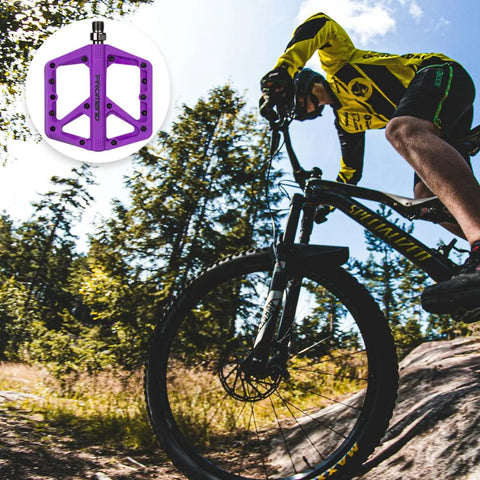 Cyclist on mountain trail with Durable Nylon Mountain Bike Pedals With DU Bearings Lightweight Platform Pedals in purple.