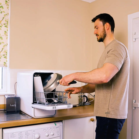 Man loading a pan into the Straight Plug Countertop Dishwasher With No Fuss Setup And Lightning Fast Fifteen Minute Cycle.