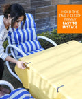Person installing stainless steel tablecloth clips on a picnic table, securing a yellow cloth with rust proof clips for parties.