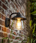 Top Shelf Premium Matte Black Wall Lantern With Slick Clear Glass Panel mounted on brick wall, illuminating outdoor space.