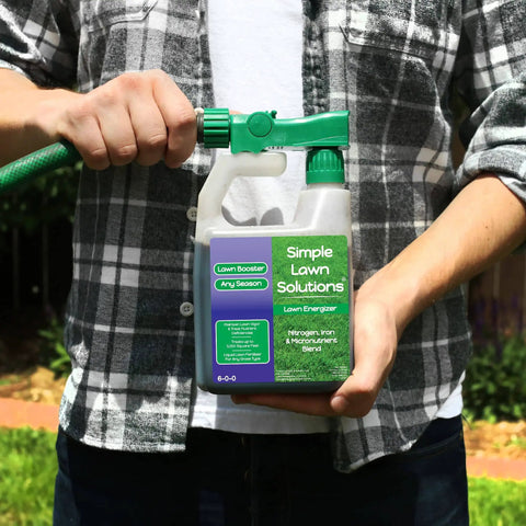 Person holding Heavy Duty Liquid Lawn Fertilizer With Iron And Nitrogen, Hose End Sprayer Included, 32 Ounce container.