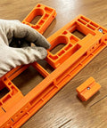 Hand adjusting the durable orange Adjustable Concealed Hinge Router Template For Seamless Cabinet Doors And Reusable Woodworking Guides.