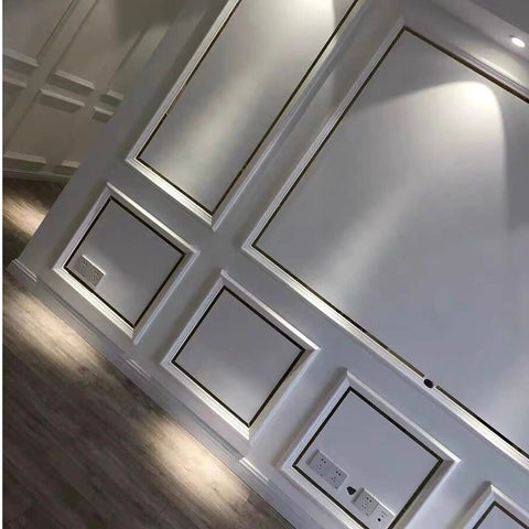 Modern interior wall with geometric panel design and spotlight, against a hardwood floor backdrop.