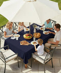 Family dining outdoors with outdoor table cover with umbrella hole and zipper 60x84 inch navy low maintenance washable waterproof tablecloth.