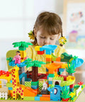 Girl playing with colorful blocks in a jungle theme, part of the Game Changing 812 Piece Building Blocks Kit Featuring Self Adhesive Wall Baseplates And Interconnected Marble Run Tracks For Kid Approved STEM Projects And No Fuss Setup.