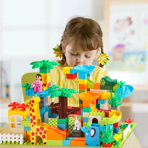 Girl playing with colorful blocks in a jungle theme, part of the Game Changing 812 Piece Building Blocks Kit Featuring Self Adhesive Wall Baseplates And Interconnected Marble Run Tracks For Kid Approved STEM Projects And No Fuss Setup.