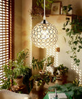 Decorative globe hanging light in botanical-themed room with patterned shadow effect on walls