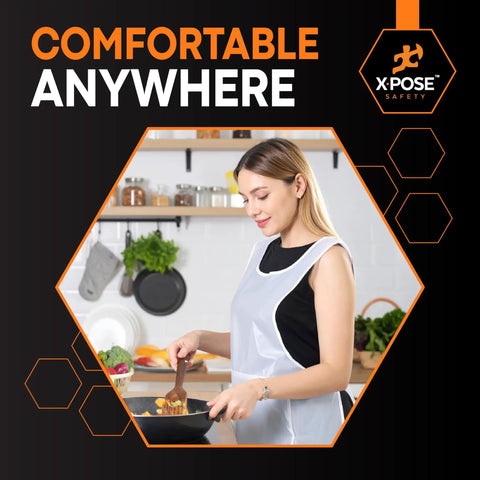 Woman cooking in kitchen wearing White Disposable Aprons 300 Pack Individually Wrapped Waterproof Polyethylene 1 Mil Durable