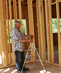 Man using a Self Leveling Cross And Line Laser Kit With GreenBrite Technology in a wooden-framed room