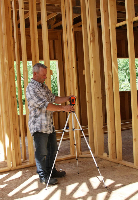 Man using a Self Leveling Cross And Line Laser Kit With GreenBrite Technology in a wooden-framed room