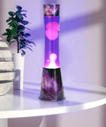 16 Inch Magma Lamp Liquid Motion Galaxy Design with Colormax White Wax in Purple Liquid Decal Base on a table near a plant.