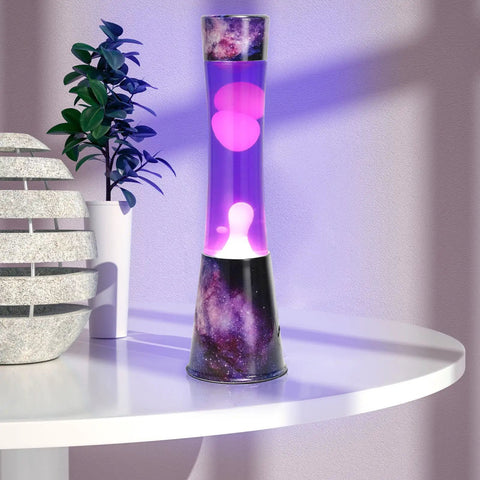 16 Inch Magma Lamp Liquid Motion Galaxy Design with Colormax White Wax in Purple Liquid Decal Base on a table near a plant.