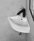 Small corner wall-mounted white sink with black faucet in modern bathroom