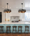 Two six light modern farmhouse chandeliers with stacked ring design in black metal and gold interior installed in a kitchen