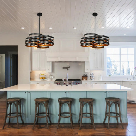 Two six light modern farmhouse chandeliers with stacked ring design in black metal and gold interior installed in a kitchen