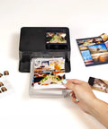 Selphy CP1500 Wireless Photo Printer In Black Ultra Portable Mini Printer With WiFi And Smartphone Connectivity on table with photos
