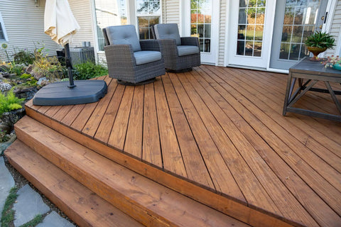 Heavy Duty Wood Stain And Sealer In One For Decks, 5 Gallon semi-transparent finish on a wooden deck with steps and chairs.