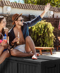 Heavy Duty 150 Gallon Waterproof Outdoor Storage Box For Patio And Garden Lockable Resin Deck Box with people seated on it by a pool.