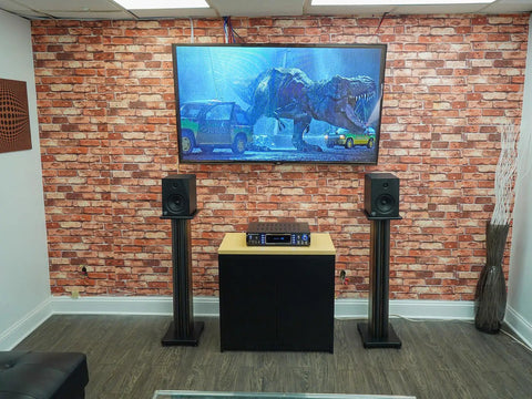 Pair 36 Inch Speaker Stands Built To Last With 100 Lb Capacity, Fixed Height, Cable Management in home theater with brick wall.