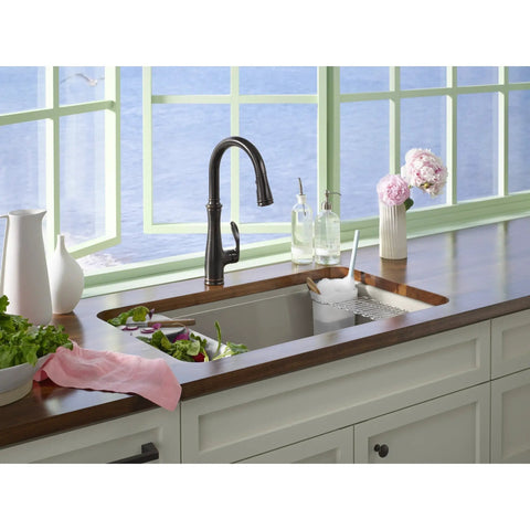 Kitchen sink with Riverby White Rinsing Colander With Built In Cutting Board in use, showing veggies rinsing and chopping area.