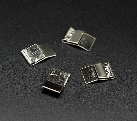 Four small rectangular silver clips arranged on a black surface, each with a textured back and smooth front.