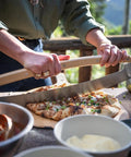 Person using Pi Pizza Rocker Cutter Pro For Effortless Slicing Of Thin Or Thick Crust Pizza With Stainless Steel Rocker Blade And Bamboo Handles