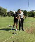 Two golfers practicing with Unisex Base Unit For Golf Swing Training Black, Adjustable Platform at a driving range