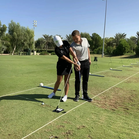 Two golfers practicing with Unisex Base Unit For Golf Swing Training Black, Adjustable Platform at a driving range