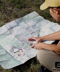 Person using TruArc10 Baseplate Compass for weekend camping on a map outdoors.