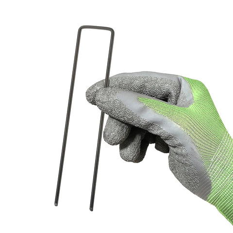 Gloved hand holding 100 Pack 6 Inch 11 Gauge Heavy Duty U Shaped Garden Staples Ground Stakes For Anchoring Landscape Fabric Spikes Pins Pegs