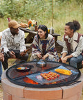 Group enjoying a barbecue on a 36 Inch Round Fire Pit Grate For Outdoor Grillin Foldable Heavy Duty Steel Campfire BBQ Grid