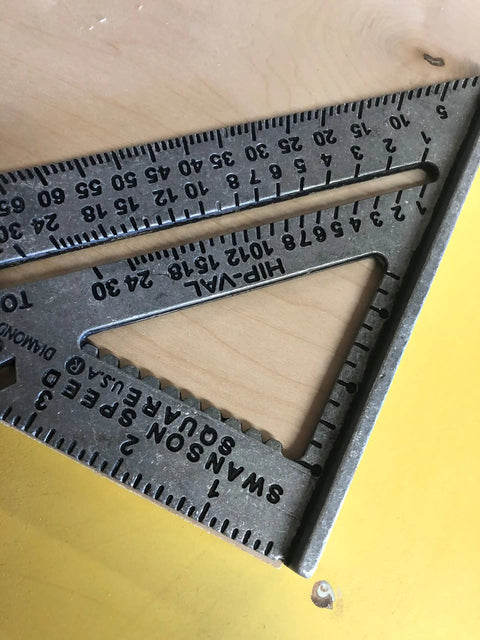 Close-up of 7 Inch Speed Square Blue For Framing And Woodworking With Multi Gradation Markings on yellow surface