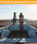 Rear view of a pickup truck with two people sitting on the tailgate looking at the desert landscape.