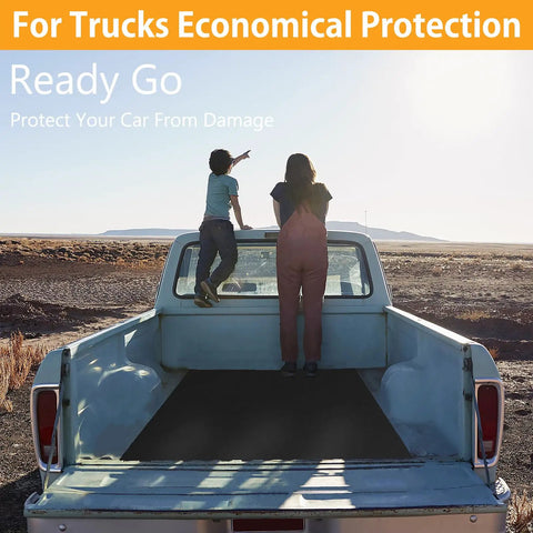 Rear view of a pickup truck with two people sitting on the tailgate looking at the desert landscape.