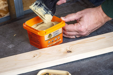 Gorilla Wood Filler tub, orange 16 oz, beige paste scooped with a putty knife (front view).
