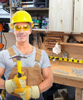 Man holding hammer in workshop, wearing safety gear, ready to use 300 Count Double Headed Skirting Nails With Seamless Finish Galvanized Steel Baseboard Trim Pins Rust Resistant Coating Guarantees Smooth Install Experience Holds Tight Every Time Dang Solid Hardware Ready To Roll For Any Diy Job.