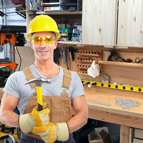 Man holding hammer in workshop, wearing safety gear, ready to use 300 Count Double Headed Skirting Nails With Seamless Finish Galvanized Steel Baseboard Trim Pins Rust Resistant Coating Guarantees Smooth Install Experience Holds Tight Every Time Dang Solid Hardware Ready To Roll For Any Diy Job.
