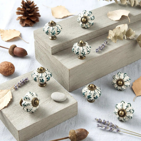 Top Tier Ivory Ceramic Pumpkin Cabinet Knobs Set Of 16 For Kitchen Drawers And Bedroom Furniture With Cute Green Floral Details And Classic Vintage Vibe For Easy Home Makeovers displayed on wooden surfaces.