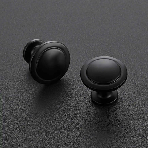 Solid Dope Matte Black Zinc Kitchen Cabinet Knobs And Drawer Hardware 1 1/4 Inch Round Disc Pulls For Cupboards 40 Piece Set on a black surface.