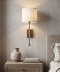 Fabric Shade Wall Sconce Vintage Brass Metal Lamp Bedside Indoor Lighting with white fabric shade and brass arm, mounted on wall.