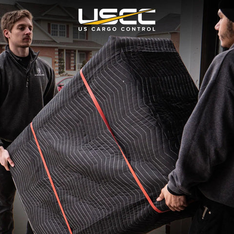 Two men carrying furniture covered with Heavy Duty Moving Blankets 72x80 Inches 4 Pack Black Padded Furniture Pads for protection.