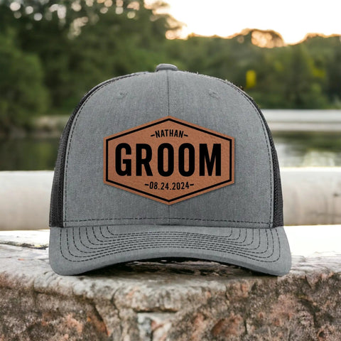 Grey trucker hat with a brown patch featuring 'GROOM' and personalized name and date, part of Groom Gifts For Men Customizable Groom Squad Hat Sets From 3 To 10, Personalized Will You Be My Groomsman Trucker Hat, Bachelor Party Golf Accessories, Best Man And Groomsman Proposal Gift.