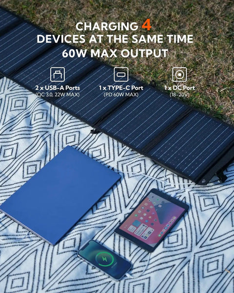 60W Foldable Portable Solar Panel Charger with PD USB C, QC3.0 USB A Outputs on a blanket with charging devices