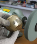 Hand holding polished brass item with Hella Durable 8 Inch Polyurethane Buffing Wheels 2000 Grit Silicon Carbide Abrasive in background.