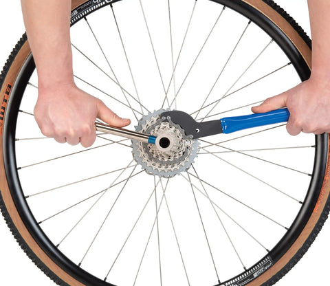 Beefy Sprocket Remover And Chain Whip Tool for 5-12 Speed Cassettes being used on a bike wheel, showcasing 15 inch durability.