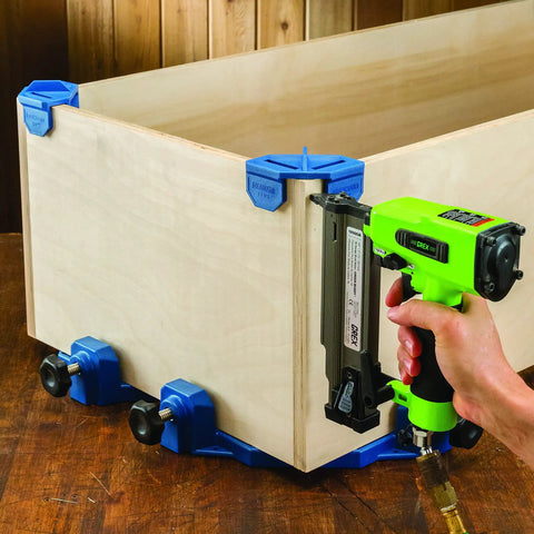 Blue Three Quarters Inch Corner Clamp Clips Four Pack For Woodworking securing corner of wooden box with nail gun in use.