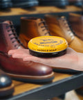 Hand holding Yellow Saddle Soap Leather Cleaner And Conditioner All In One For Boots Kicks Bags Saddles And More Soften Dry