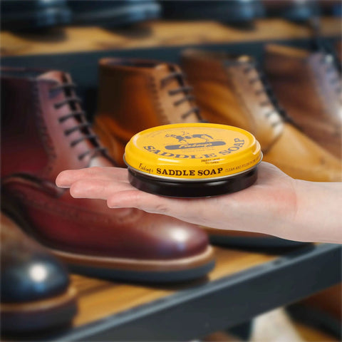 Hand holding Yellow Saddle Soap Leather Cleaner And Conditioner All In One For Boots Kicks Bags Saddles And More Soften Dry