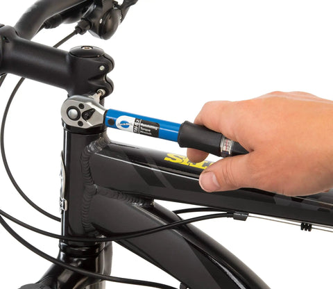 Hand using Ratcheting Torque Wrench With A 2 To 14 Nm Range And 18 To 124 Inch Pounds Readout Three Eighth Inch Drive on bike